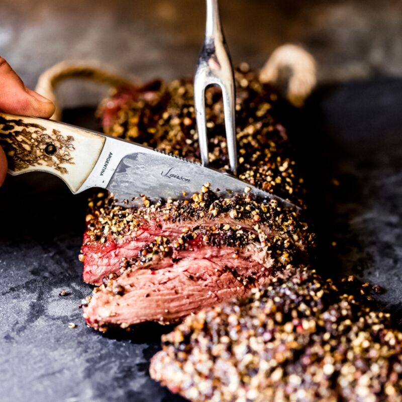 slicing whole elk tenderloin with hunting knife